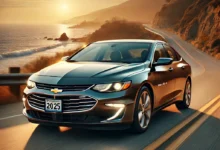 2025 Chevrolet Malibu driving on a coastal highway at sunset.